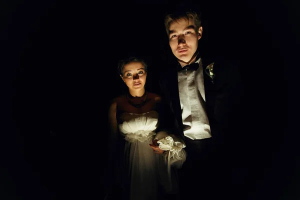 Braut und Bräutigam sehen geheimnisvoll aus, wenn sie im dunklen Raum stehen — Stockfoto