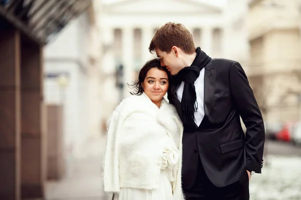 Groom penche vers la tête de la mariée tandis qu'elle se tient derrière lui un co de fourrure — Photo