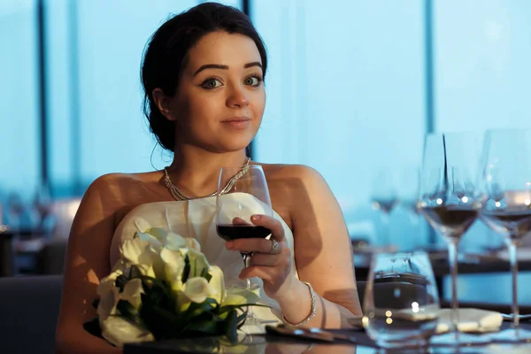 Linda noiva morena segura um copo com vinho sentado em um empate — Fotografia de Stock