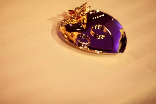 Zlaté snubní prsteny leží na malou desku na beig tableclot — Stock fotografie