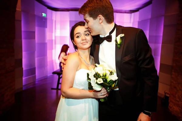 Groom abraça uma noiva terna de pé com ela em um restaurante — Fotografia de Stock