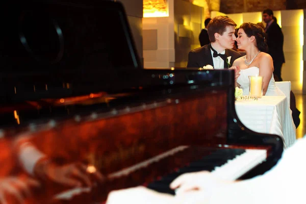 Una mirada desde detrás de un piano en la encantadora pareja de bodas —  Fotos de Stock