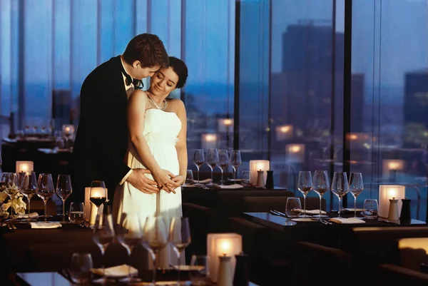 Newlyweds in a family way stand in an empty cafe in the evening — Stock Photo, Image