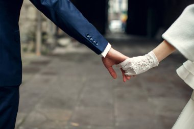 Damat gelinin kol beyaz eldiven şehirde yürüyüş tutar