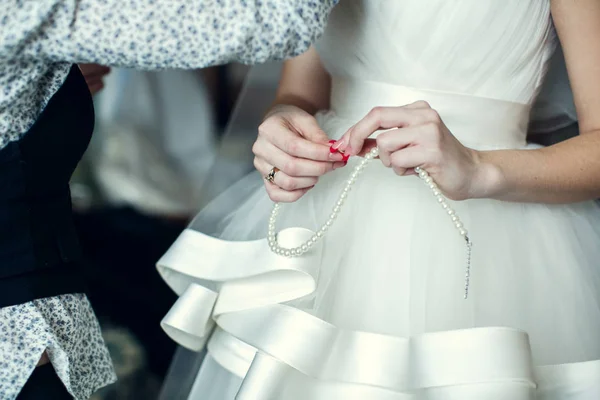 Finom menyasszony gyöngy nyaklánc tartja a karjában — Stock Fotó
