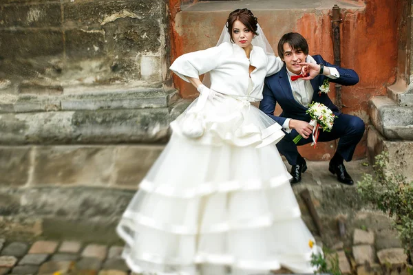 Жених сидит на корточках на каменном шагу позади невесты — стоковое фото
