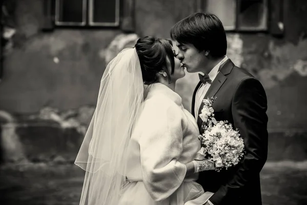 Черно-белая фотография целующихся молодоженов, стоящих на постаменте — стоковое фото