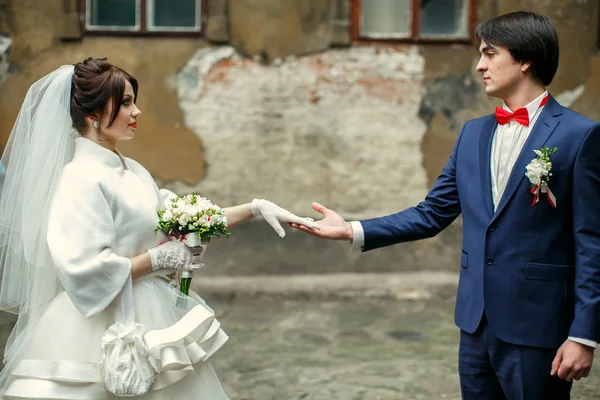 Groom olha com amor para uma noiva segurando seu braço em uma luva branca — Fotografia de Stock