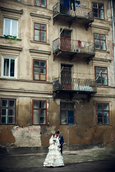 Güzel düğün çifti eski yarı harap balkon altında duruyor — Stok fotoğraf