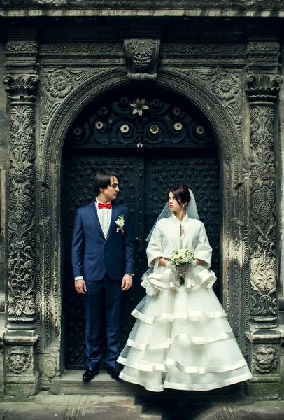 Los recién casados se miran uno al otro de pie detrás de una vieja puerta de acero — Foto de Stock