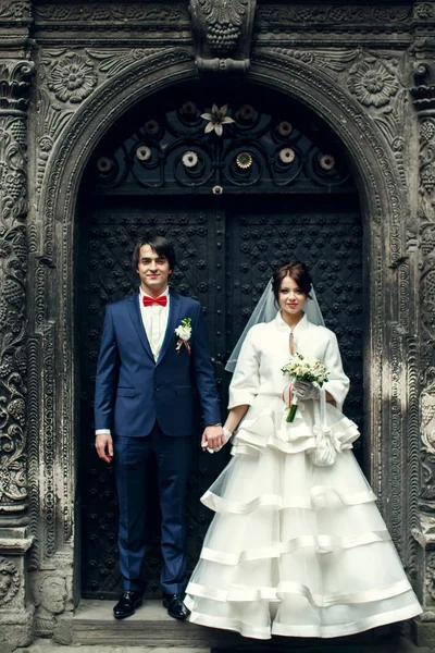 Bride and groom hold each other hands standing behind an old ste — Stock Photo, Image