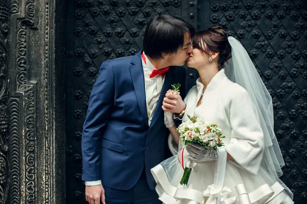 Groom kisses a bride holding his arm behind his heart — Stock Photo, Image