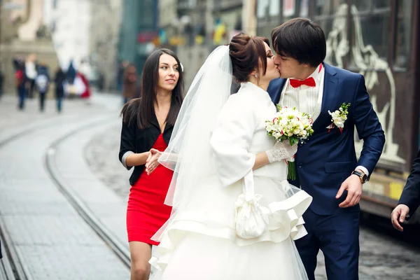 Mireasa sărută un mire în timp ce se plimbă cu prietenii în jurul orașului — Fotografie, imagine de stoc