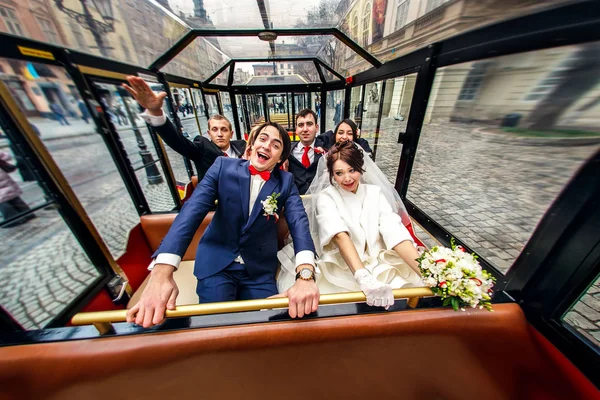 Новобрачные сидят в туристическом трамвае вместе с друзьями — стоковое фото