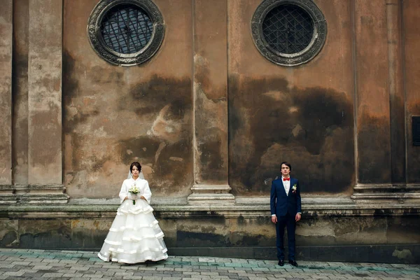 新婚夫妇站在一边的老讲座圆窗下 — 图库照片