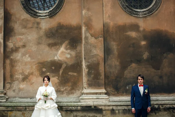 Серйозна наречена і наречена стоять під круглими сталевими вікнами олова — стокове фото