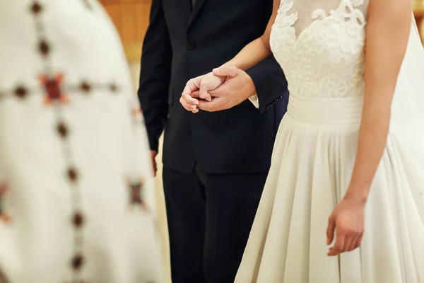 Жених и невеста крепко держатся за руки, стоя перед — стоковое фото