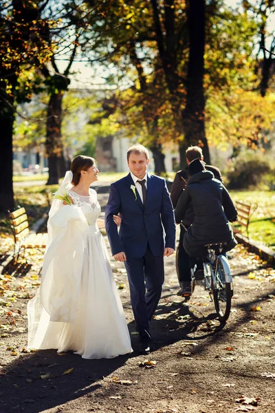 幸せな新婚夫婦が秋の公園を歩く — ストック写真