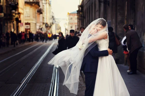 Braut umarmt einen Bräutigam, der unter ihrem Schleier versteckt ist — Stockfoto
