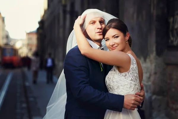 Noiva coloca um véu na testa do noivo, enquanto ele a abraça no o — Fotografia de Stock