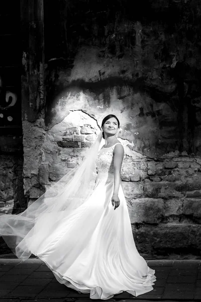 Sun illuminates a brunette bride posing on the old street — Stock Photo, Image