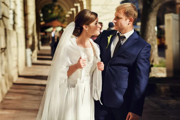 Os recém-casados olham um para o outro em pé na rua em um su frio — Fotografia de Stock