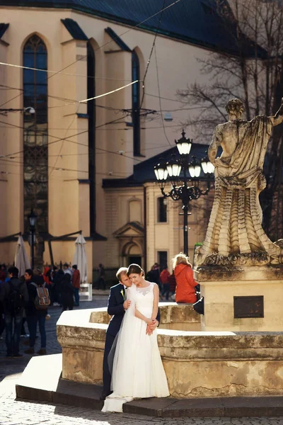 Sposa si appoggia a uno sposo mentre si siedono dietro una vecchia fontana — Foto Stock