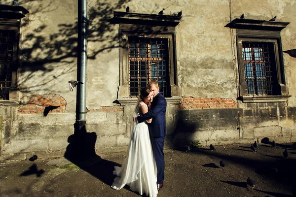 Sposo tiene sposa tenera in piedi dietro una vecchia casa — Foto Stock