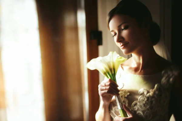 Bride holds a tender bouquet of callas behind her face — Stock Photo, Image