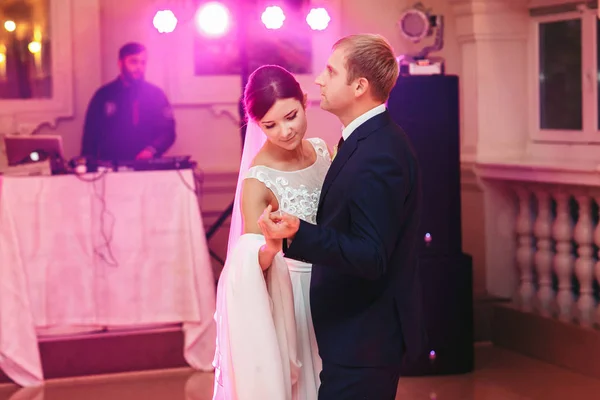 Mariée regarde vers le bas en dansant avec un marié dans des lumières roses — Photo