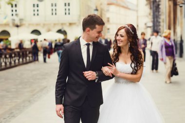 Damat gelin elini tutarak cadde boyunca yol açar. 