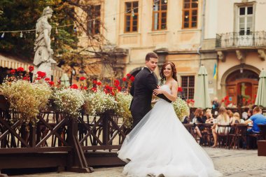 Damat gelinin bel ahşap bir sokak kafe poz tutar 