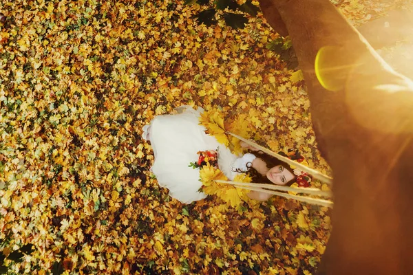 Zon schijnt over een bruid die in een krans op de schommel zit — Stockfoto