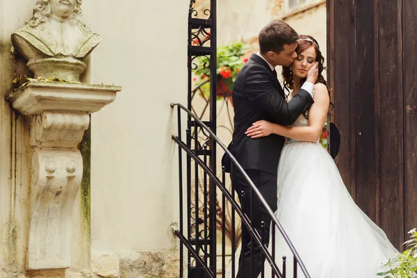 Groom segura o rosto do bide tenro de pé com ela nas escadas o — Fotografia de Stock