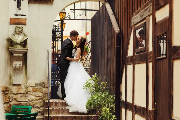 Bride et marié se tiennent dans une arche de pierre qui mène à la rue — Photo