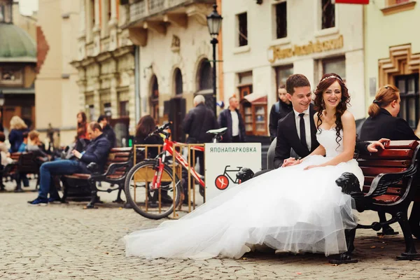 Gelin Damat ahşap bir banka ile köpüklü oturma gülümsüyor — Stok fotoğraf