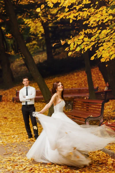 Tendre mariée tourbillonne sur le col plein de feuilles d'automne — Photo