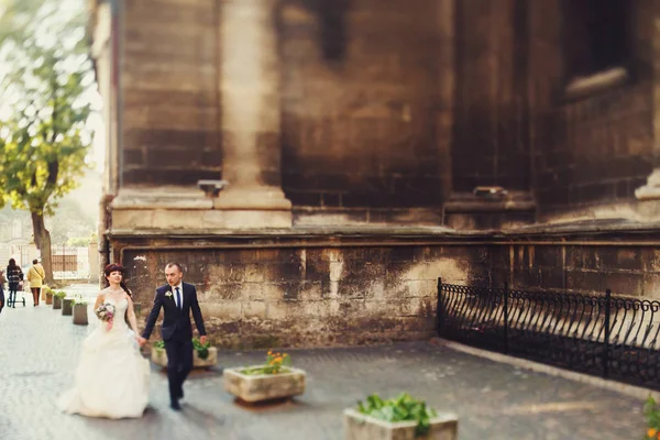 Um olhar de longe sobre os recém-casados andando ao redor de uma velha catedra — Fotografia de Stock