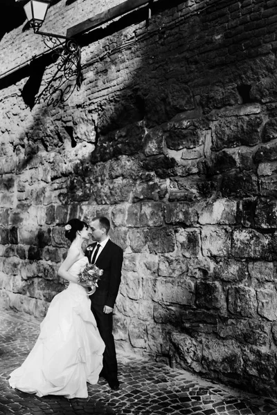 Un moment avant un baiser de jeunes mariés debout sous le vieux mur — Photo