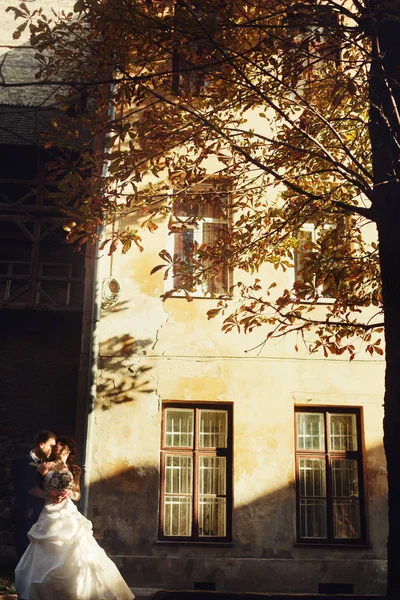 Sposa e sposo bacio in piedi nella parte anteriore di un edificio illumina — Foto Stock