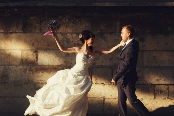 Brudgummen fångar brudens hand medan hon försöker pressa honom med en bo — Stockfoto