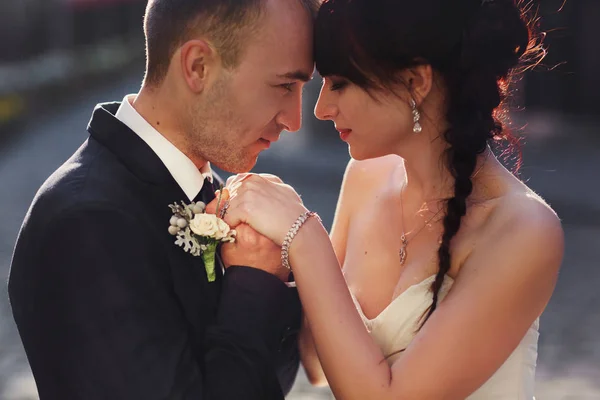 Жених нежно держит руки невесты, пока она прислоняется к его плечу. — стоковое фото