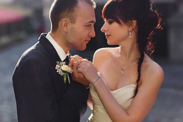 Groom olha para uma noiva seriamente segurando seus braços delicados — Fotografia de Stock