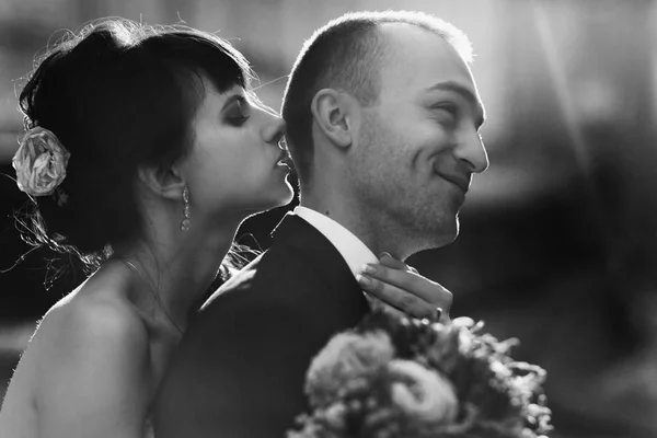 Groom sorri sinceramente enquanto a noiva tenta beijar a cabeça de b — Fotografia de Stock