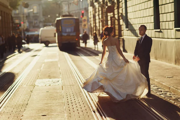 Bruid houdt haar jurk omhoog terwijl je met een bruidegom op de tram — Stockfoto