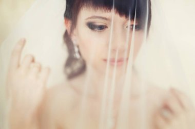 Gelin düşünceli ayakta hassas bir peçe altında görünüyor 