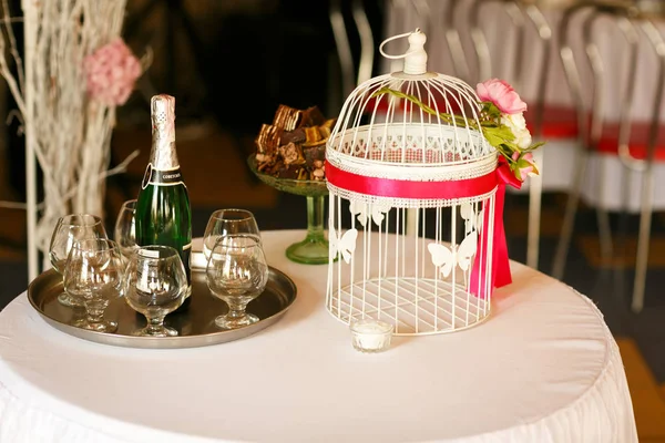 Decoração de mesa de casamento. Gaiola de pássaro branco com fita vermelha sobre ele — Fotografia de Stock