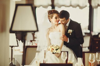 Hassas beyaz gelin omuz ayakta hall ile damat kisses 