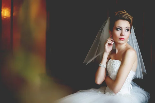 Взгляд издалека на вдумчивую невесту, сидящую в темной комнате — стоковое фото