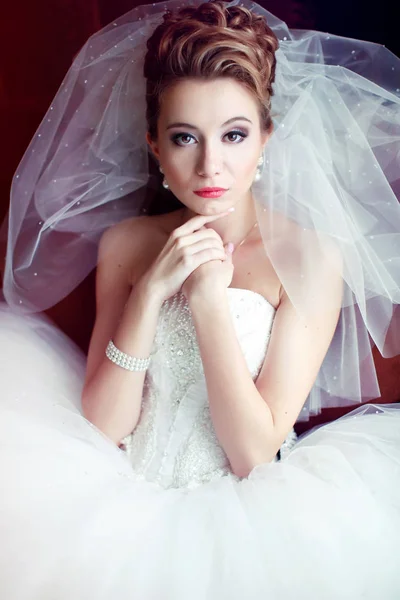 Bride sits in a big chair holding her thin hands behind her face — Stock Photo, Image